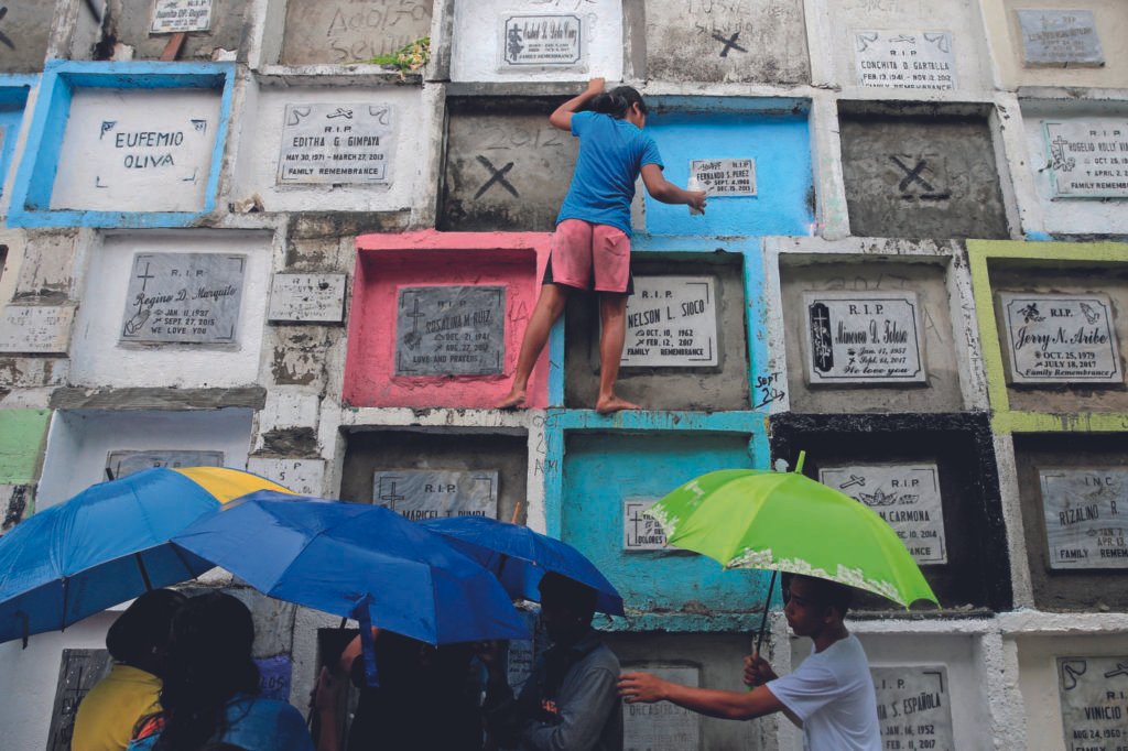 Gente llevando velas y flores en un cementerio en Manila, Filipinas.