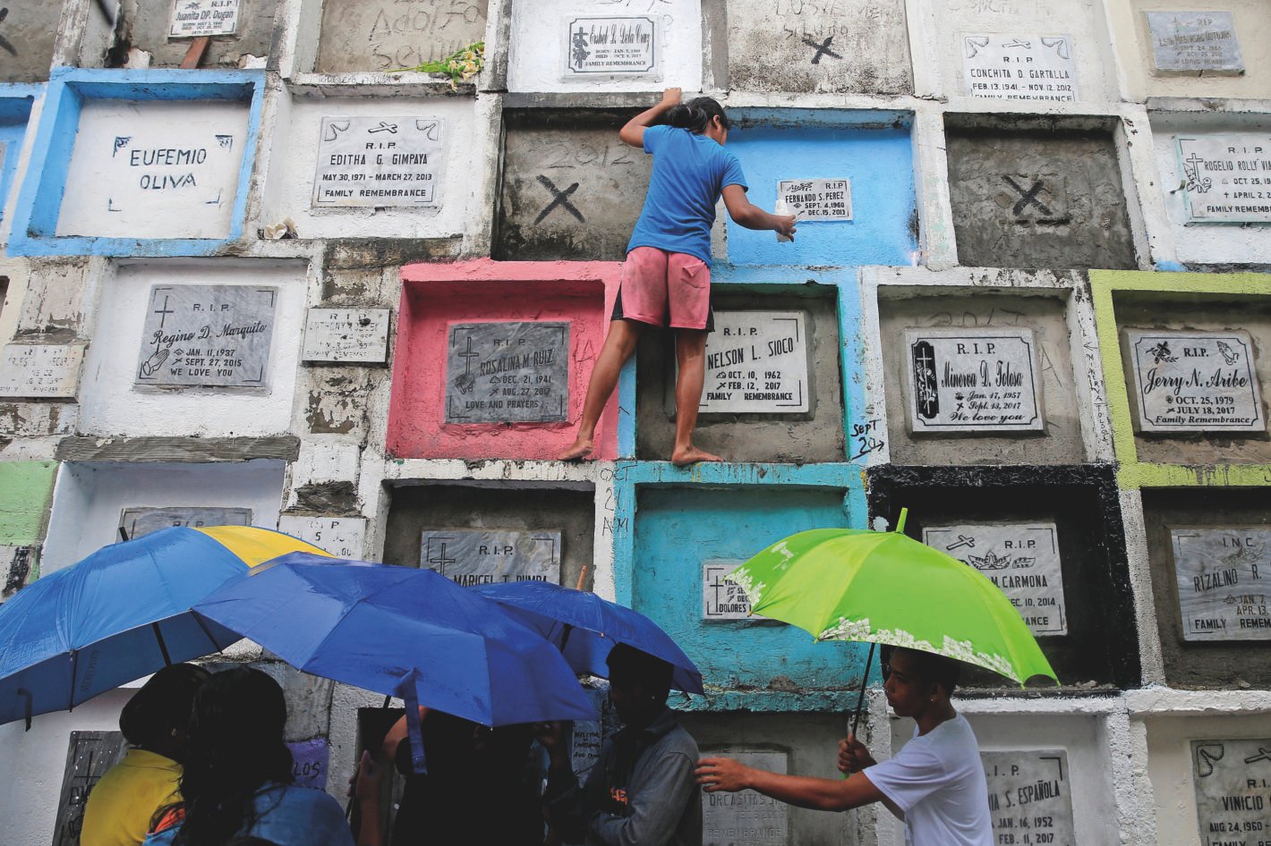 Gente llevando velas y flores en un cementerio en Manila, Filipinas.